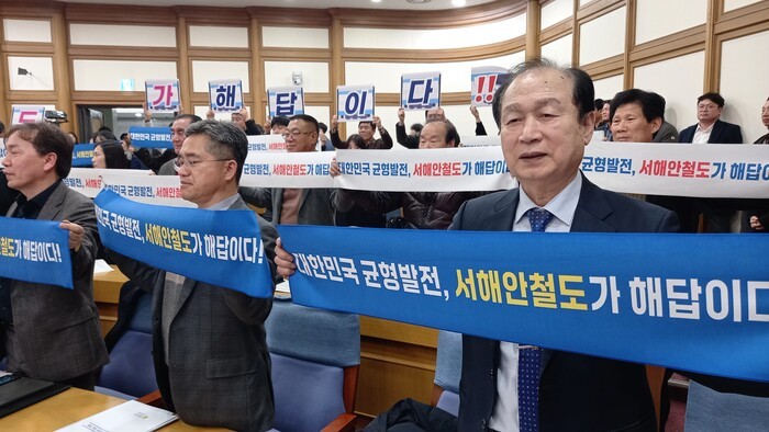 <br>
정회근 상임대표가 전북·전남 지역 8개 지방자치단체 주최 ‘서해안철도 건설 국회 정책포럼’(3.18)에 참석해 서해안철도가 제5차 국가철도망 구축계획에 반영될 것을 촉구하는 퍼포먼스를 하고 있다. (사진=정회근 상임대표)<br>
