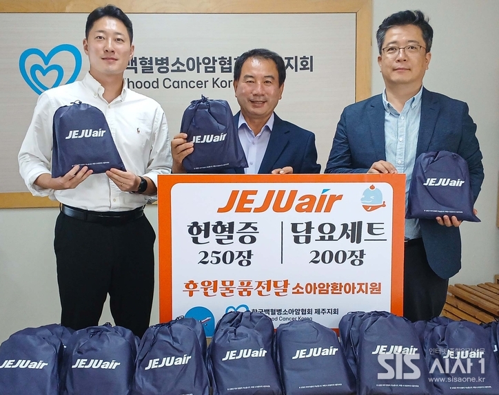 제주항공 김정제 산업안전보건팀장(오른쪽)이 10월 15일 한국백혈병소아암협회 고경남 제주지회장(가운데)에 헌혈증과 담요 등 여행용 키트를 전달한 뒤 기념촬영을 하고 있다. (자료 = 제주항공)